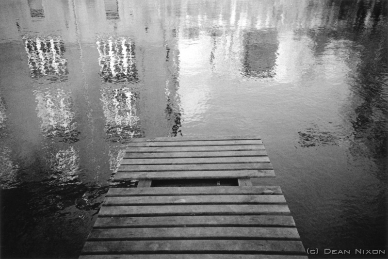 2001.09 Karl-Heine Kanal Jetty_hf <div align=left>September 2001<br>As I write, dark clouds portend the demise of summer, and tomorrow morning, with thousands of neo nazis and radical lefties threatening to clash when they march through the centre of Leipzig (citizens are being warned to stay out of town).<br>Seems that not all is well in Europe, with its feeble economic performances, the threats posed by unstable left and right wing politics, and the deadly legacies of oppression not too far from the the ECs borders (watch Belarus as well as Chechnya and Macedonia!)<br>I experienced a "newer" but still mild form of racism a couple of weeks ago when I and an american friend were pushed out of a bar by a large doorman, with an inebriated native shouting, "Schei Amerikaners"   but this attitude is nothing unusual here now (blame the foot in mouth GWB for that!). However, I saw a tram driver re open the front door for a young Vietnamese man running to catch a ride even as he was starting to move away from the stop (they normally wont even wait for the little old German ladies!) Maybe its not over yet.<br>This months picture is another from my series on a canal system in Leipzig. Next month, maybe a wedding in an old castle...a happier picture?...we can but hope.<br>D.<br>