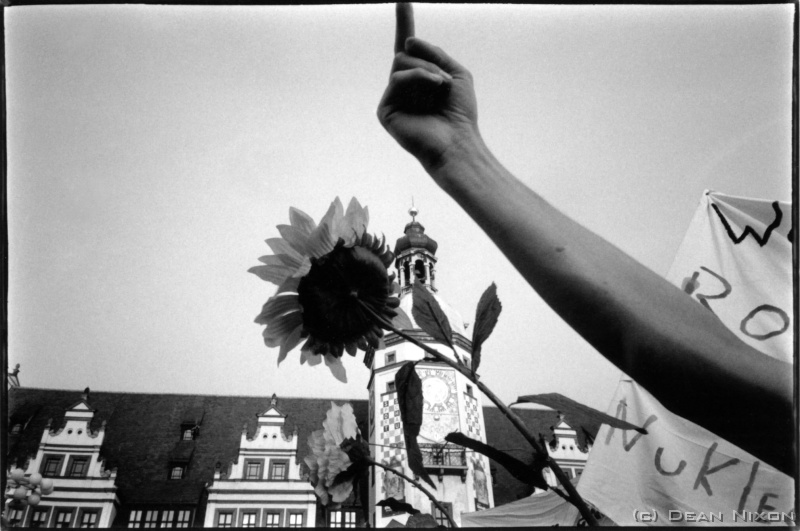 2002.10 Anti Stoiber Demonstration_hf <div  align=left>Oct 2002<br>Dear Unwashed                                      <   just kidding,<br>(Didnt want to say this, but...the truth must out..!)<br>Political change here in Germany is much like the weather, & may be criticised for being teutonically slow & boring, but its deliberate, and from time to time awesomely important.<br>The drama now is the war of words between the newly re-elected Schrder & G. Bush jnr. <br>The pic (XA4, 28mm, Tri X) is from a very anti Stoiber rally in the centre of Leipzig   which was as enlightening as it was funny! He was protected by bodyguards who comically raised umbrellas like clockwork to protect him from a barrage of eggs & tomatoes, while his speech was all but drowned out by the hecklers. The right-of-centre Barvarian candidate for the Chancellors job is not loved here   where former East Germany first embraced democracy 12 years ago! <br>Anyway, Schrder kept his job by the narrowest of margins (no count controversy either!), and was almost certainly aided by his reminder to a belligerent US that the modern world has evolved mechanisms to protect us from despots who attempt to usurp democracy: the precious, though perhaps feeble at times, UN. So now, as we (in Europe) see the US, the so called founder of democracy (& actually it was France first!), throwing its weight around including even suggesting Schrder resign immediately, its no surprise that Germany feels it has something significant to say. The Germans can never forget that they, thanks in large part to the Americans, were themselves rid of a monster once before (the mere mention of whom still causes scandals)   and thus are certainly not willing to throw away these hard won democratic principles to satisfy the whims of one who says "Join us, or you are our enemy"!!!<br>Do not be mislead, Germans in general are NOT anti-American - but, among many others, they want democracy upheld! (Mal sehen!).<br>So there!...vented my spleen a bit.<br>On a different note: a defender of the truth, Roddy Scott, aged 31, was killed, shot through the eye, while filming in Chechnya, Sept 26th.<br>RESPECT PLEASE!<br>: |<br>Opinionatedly yours,<br>Dean<br>PS. The promised piece on matters of the heart and stomach should appear next month.<br>