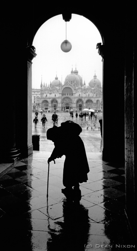 2004.01 Venice Beggar_hf <div align=left>Jan 2004<br>Dear Patient Readers,<br>Having read far too much Hemingway in the last few months, and wanting a break from Germany:<br>It was dark, foggy and cold as the night train pulled out of the Leipzig station just after Christmas. I had a tiny bed in a sleeping compartment and quickly fell asleep; a half-sleep, dreaming and half-waking at various stops, until arriving in Munich just before dawn. Enough time for a quick coffee (which I notice tastes better the further south one travels in Europe!) and then settled into the train to Italy. Passing through the grey Alps, watching as a wintry light slowly increased and then emerging into warm valleys, made me realise that if Id flown I would have missed far too much. To fly would have been cheaper and much faster (but...!)<br>Shortly after midday I was in Venice. The fabled, faded and fabulous Venice: every bit what the books and films and music and works of art pay homage to. Everything you heard is true, but you cant realise what it means until you go there!<br>Still, I only had a few days, so with a cheap hotel sorted in 10 minutes, I was off to explore...and photograph of course. And I did - cliches galore but it doesn't matter - you could spend days in one tiny alley or canal or plaza/piazza/piazzola (whatever they call them) or on a bridge, just watching. It even crossed my mind that this was a place that could be photographed in colour! ...so shocked I immediately rushed into Harrys Bar for a mind numbing martini. Just kidding about the drink - you need a wad of notes for a drink in some of the bars here, but I did allow myself a couple of espressos in the Gritti Palace bar where EH stayed and set "Across the River and into the Trees".<br>However, I managed to leave the sinking city as reluctantly but in somewhat better condition than his autobiographical character and arrive back "home" in time to celebrate New Year in the usual mad German style...back to the classrooms, and late sessions in darkrooms; but I bet Papa Ernest would never in his darkest hour have stooped to write postcards from a McDonalds in a dead industrial suburb...and then ride a bike home in the icy drizzle at 2 oclock in the morning...!<br>Naja, so ist das Leben.<br>Dean<br>