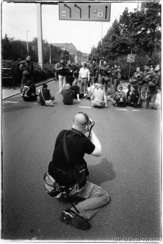 2004.05 Stefan Hoyer.Photographer_hf <div  align=left>12 May 2004<br>Dear Workers,<br>The 1st of May - Labour Day - is usually a bit of a knees up in Europe, and it was certainly no exception this time. First of all, the EU just got a lot bigger with the addition of 10 new countries, which is gonna create a whole new scene one way or another - a possible influx of people looking for work for a start (always makes the Germans a bit nervous!). And, staying with the subject of foreigners, add hate and youve got a speech for a bunch of unhealthy, uneducated, unemployed yobbos with no hair - better known as neo-Nazis!...who, as usual for the 1st of May, turned out to march in certain cities all over Germany, irritating decent folk with their chants, banners, symbols, tattoos, and slogans on t-shirts (such as "Opa war in Ordnung" = Grandad was right). Also present in equal numbers but scattered along the routes to heckle were the far left, who some believe are as bad if not worse.<br>Anyway, this particular march in Leipzig was relatively uneventful. The 900 intellectually underendowed were escorted by around 1000 armed cops in full body-armour (to protect them from small bands of drunk and anaemic punks) most of the way to the Volkerschlachtdenkmal which is a huge stone momument commemorating the defeat of another little man with big ideas (Napoleon) but were thwarted a few hundred metres short of their goal cos the city government had quietly arranged for a school concert to be held there. Because Leipzig has a special status as a "city of freedom", democracy rules, so these marches have to be permitted despite the overwhelming opposition, not to mention the security costs and disruption to traffic - and the neo-nasties intend to stage(attempt) at least four more marches here this year!<br>Listening to the pre-march pump-up speech by their leader, Hamburg lawyer Christian Worch, was funny in an eerie sort of way - especially when his rantings about foreigners taking jobs reached the pitch and delivery style (deliberately Im sure) of "the one whose name should not be mentioned"! I managed to get close enough to get a good snap of him as he saw me and scowled, and then yelled at me about what might have once happened to a long-haired lout like me - I smiled and said "danke" (and left!)<br>By the way, the bum in the foreground belongs to a mate of mine, Stefan Hoyer, who also works at the Punctum agency. Nice guy who doesnt say much, just gets on with the job - and does a good job - without making a fuss. We worked this march together without flashing press credentials to avoid undue attention (you dont want your mug ending up on a neo Nazi website), although I did get a good truncheon prod in the chest for not moving back quickly enough when the green gorillas decided to clear the street a bit, but no bruise thanks to a thick notebook in my breast pocket. Note: long hair is gonna mark you as a lefty in such situations (or, listen to your mother!)<br>Stefan used his Nikon F100 D (which is for sale, so gizza call - Ill get you a good deal), and I went with my small but extremely practical Olympus XA4 loaded with my last roll of old formula Tri X - which Im likely to replace with Neopan 400 since Kodak has (#@!!!%) halved the silver content in their new "improved" version...!<br>Mens Day here next week - and its a national holiday! Germany can be so cool sometimes! Then, Im doing seven weeks in the old coal mines near Poland...no, not cos I did anything bad...more about that later.<br>L8r,<br>Dean<br>